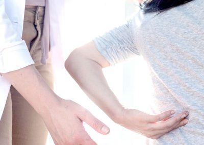 A clinician examining a patient's back during a spine consultation.
